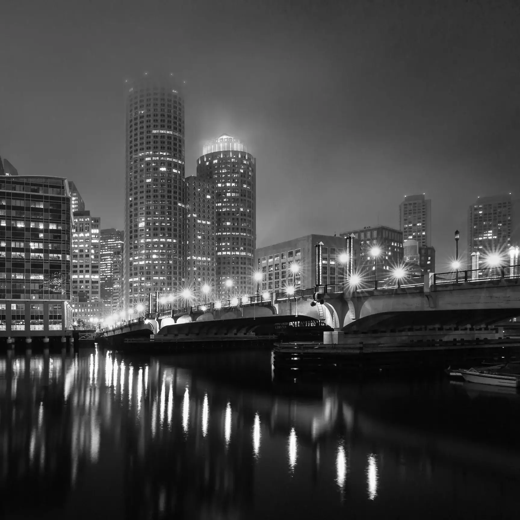 Boston skyline glowing at night with reflections on the water