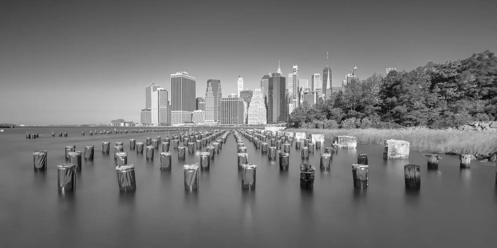 Manhattan skyline at dusk viewed from Brooklyn Bridge Park with pilings