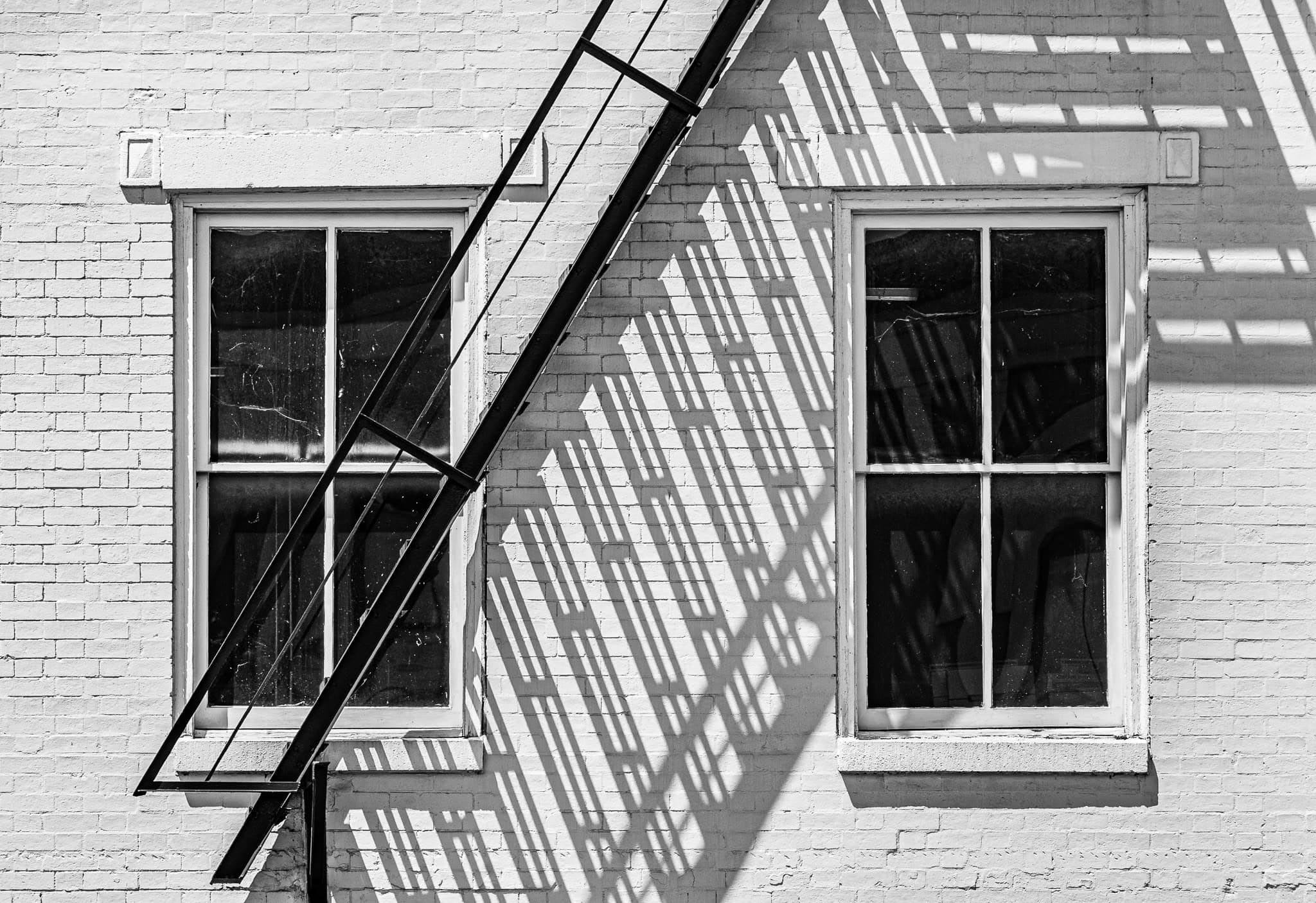 Two old windows with fire escape on aged brick building